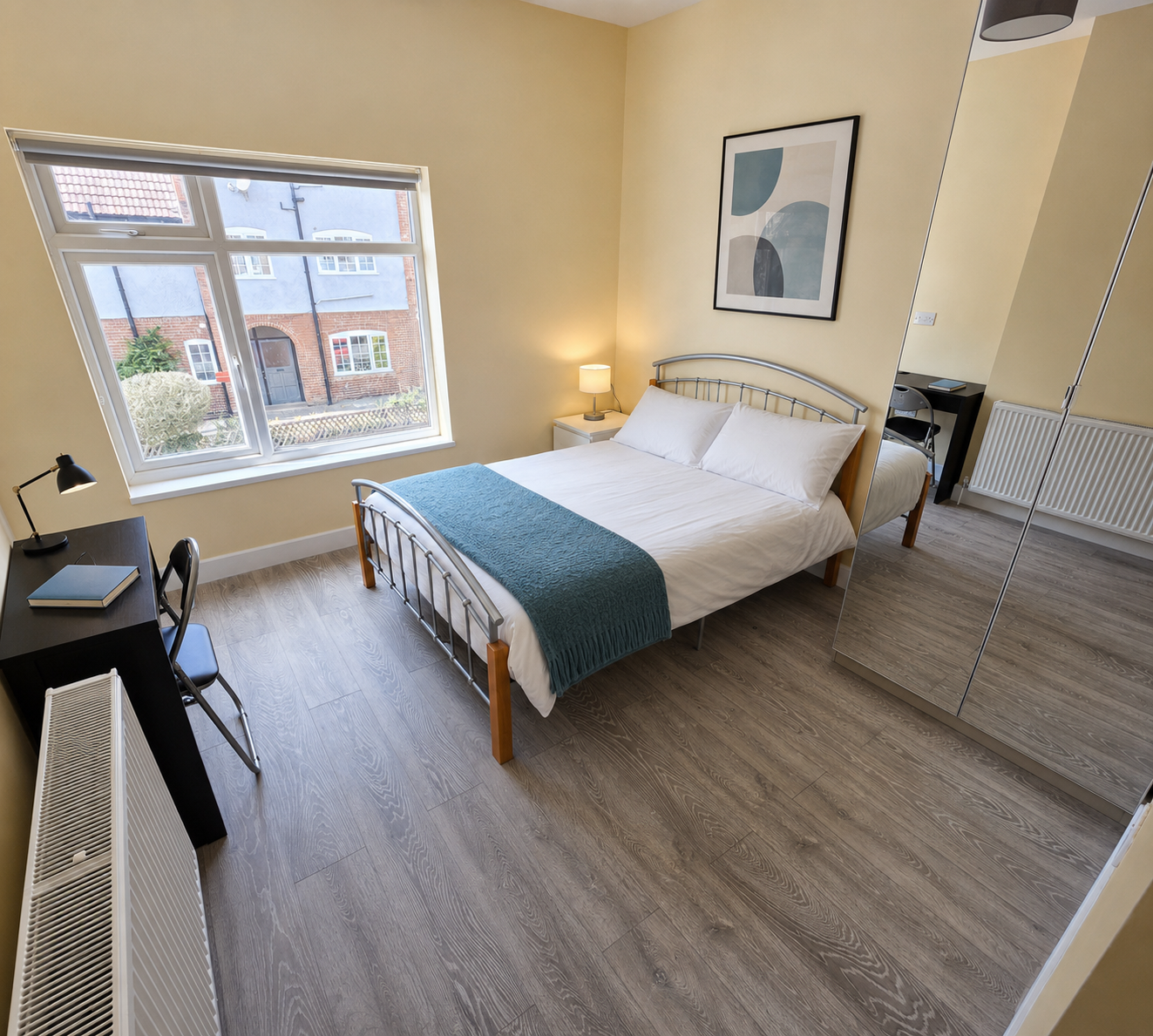Furnished bedroom with a double bed, desk, storage and a window.