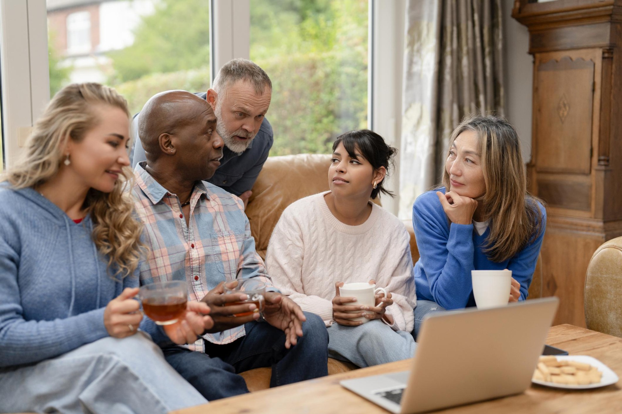 A small group of adults talking together over drinks around a table.